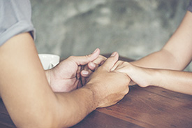 close up of hands holding each other over a desk