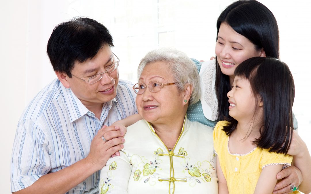 A young family surrounds an older woman with love and affection. They are on the lookout for common scams that victimize seniors so they can protect her