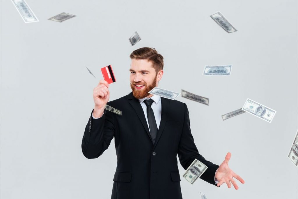A business man holding a credit card with $100 dollar bills flying around him. Are your caretakers acting suspicious?