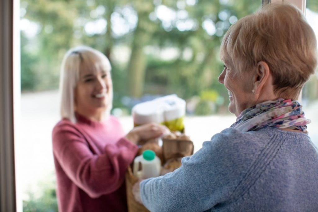 A woman delivering groceries to an older adult woman. Not all caregivers are suspicious or have ill intentions. 