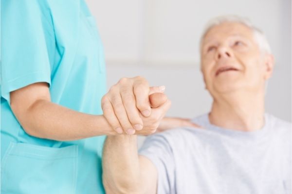 older adult male holding hands with a caregiver