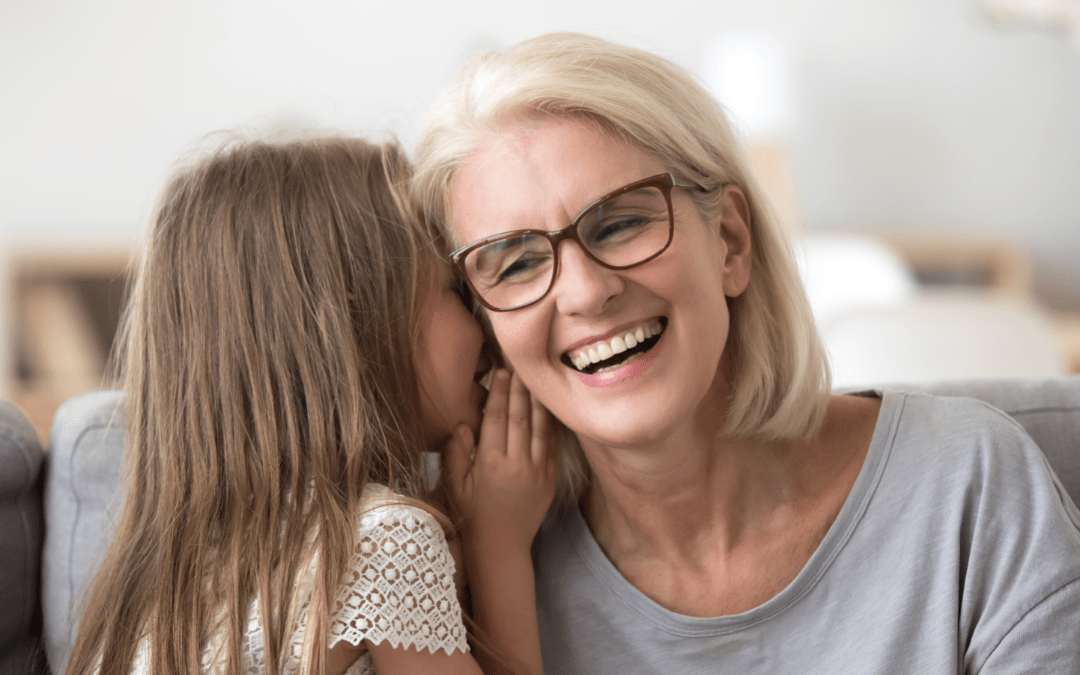 image of a child telling an adult a secret. the adult is smiling.
