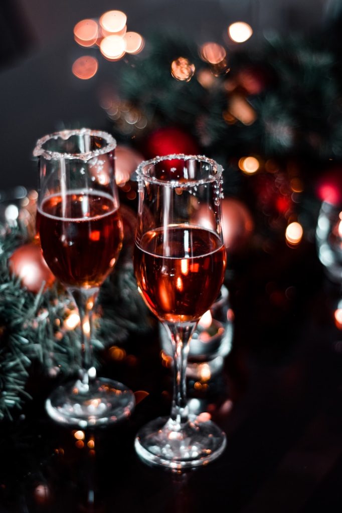 Close up of two champagne glasses filled with rosé on a Christmas evening. Holiday gift giving can be an experience.