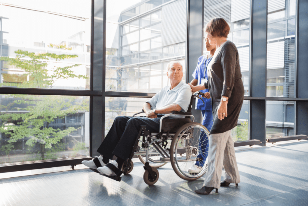 do you know how to qualify for tenncare? Image is of a man in a long-term care facility. He is taking a walk with a nurse and his partner. 