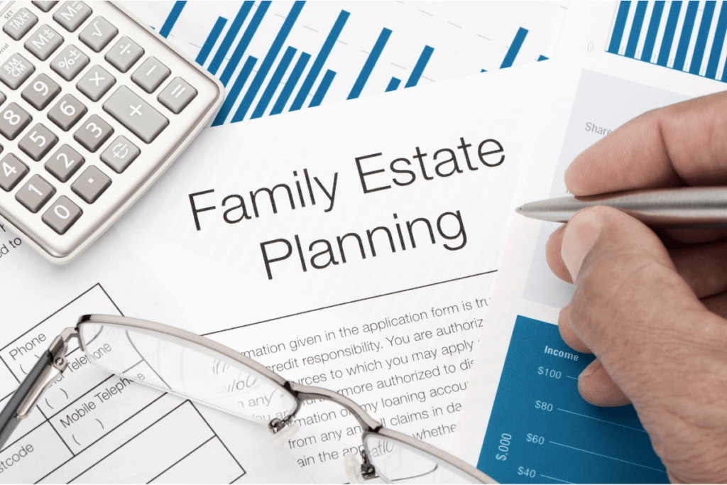 pile of papers that belong to a family estate plan with a trust and inheritance. there is a close up of a hand holding a pen, glasses, and a calculator