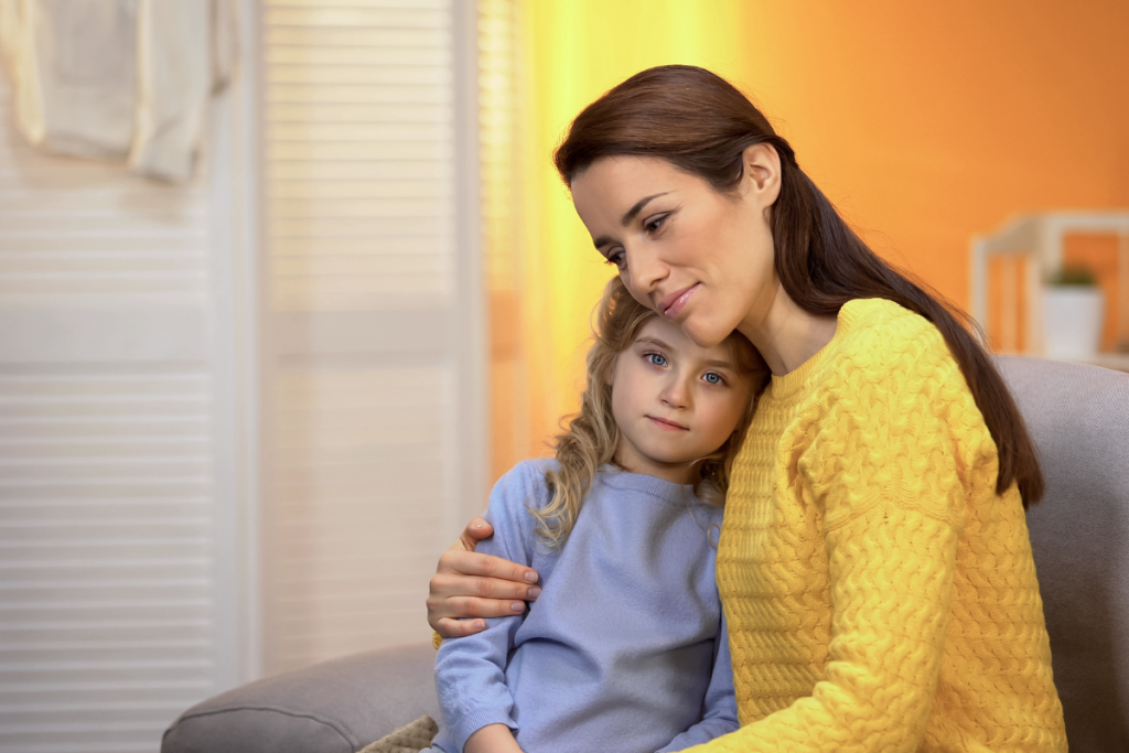 Young woman hugging a child. The child looks a little sad. The adult looks pensive. Appointing a legal guardian for your child in your will is an important decision to make. 