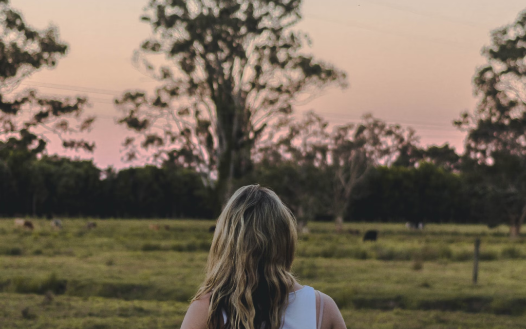 A woman with blonde hair and a guitar on her back gazes at the sunset as she decides whether she's ready to become a primary caregiver for her loved one.